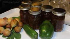 several jars filled with pickles and green peppers on a white plate next to garlic