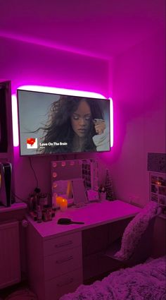 a bedroom with purple lighting and a flat screen tv mounted on the wall above a desk