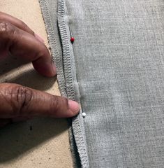 someone is stitching the side of a piece of fabric with their thumbnails