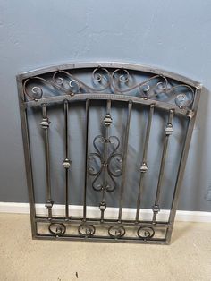 an iron fireplace screen with scroll work on the top and bottom, against a blue wall