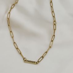 a gold chain necklace with a name tag on it and a link that says parker