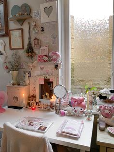 a white desk topped with lots of pink stuff animals and other items next to a window