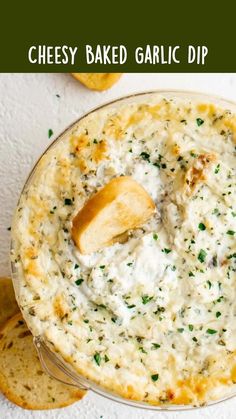 a bowl filled with dip and crackers on top of a white table next to bread