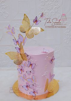 a pink and gold cake with butterflies on it