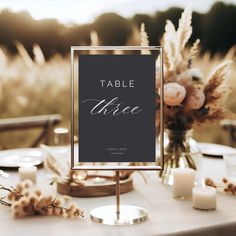 a table with a sign that says table twice on it next to candles and flowers