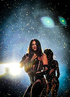 a woman standing on top of a stage in front of a light and confetti