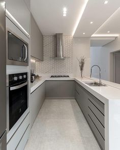 a modern kitchen with stainless steel appliances and white counter tops, along with an island in the middle