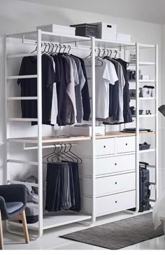 an open white closet with clothes hanging on the rails and shoes sitting on the shelves