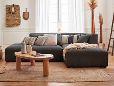 a living room filled with furniture and pillows on top of a wooden floor next to a window