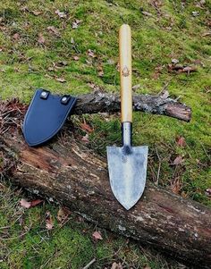 a shovel is laying on top of a fallen tree branch in the grass next to a knife