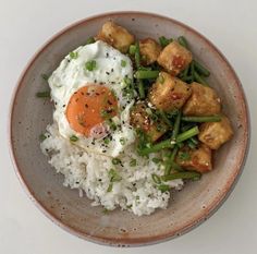 a bowl with rice, meat and vegetables in it on top of a white table