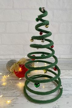 a green christmas tree with lights around it on a white wooden floor next to a brick wall