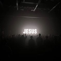 the word jesus is projected on a dark background in front of a group of people