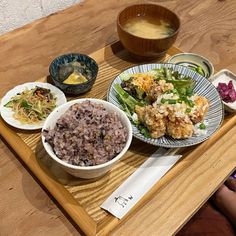 a wooden table topped with plates of food and bowls of soup on top of it