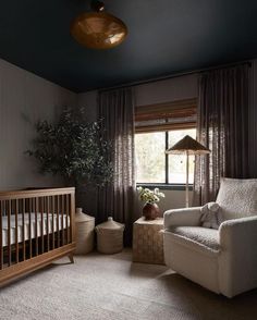 a baby's room with a crib, rocking chair and large potted plant