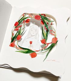 an open book with paper cut out of it and flowers in the middle, on top of a white surface