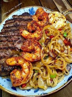 a plate with noodles, meat and shrimp on it