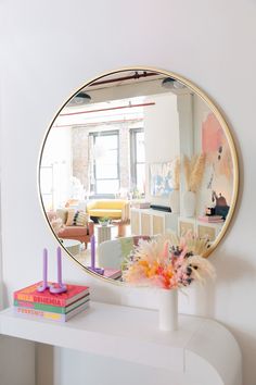 a mirror sitting on top of a white table next to a vase filled with flowers