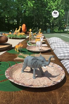 there are many small elephant figurines sitting on plates that have been placed on the table