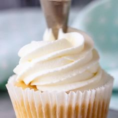 a cupcake with white frosting sitting on top of a table