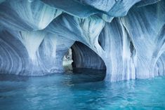 the inside of an ice cave with water flowing from it's walls and blue waters