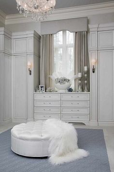 a bedroom with white furniture and chandelier