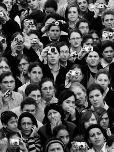 a large group of people taking pictures with their cell phones