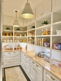 a kitchen filled with lots of white cupboards and counter top space next to a wooden floor