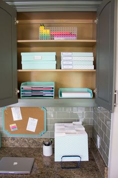 an open cabinet in a kitchen with papers and binders on the shelf above it