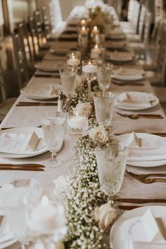 a long table is set with white flowers and candles for a formal dinner or party