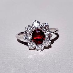 a red and white diamond ring sitting on top of a table