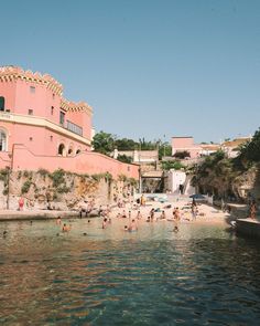 people are swimming in the water next to a pink building