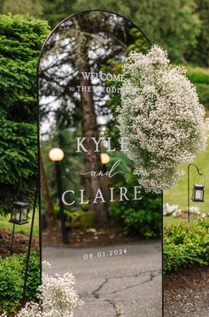 the welcome sign for kyle and claire is shown in front of some bushes with white flowers