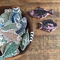 three fish magnets sitting on top of a wooden table next to a knife and fork