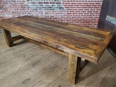 a wooden table sitting on top of a hard wood floor next to a brick wall