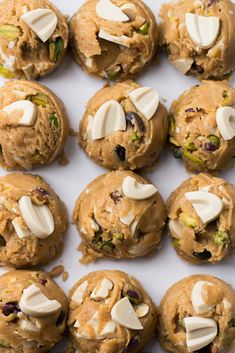 several cookies with nuts and other toppings on a white surface, including almonds