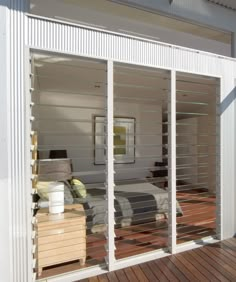 a bed sitting on top of a wooden floor next to a sliding glass door covered in blinds