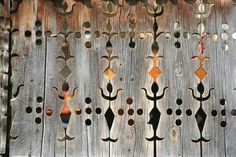 a wooden fence with several decorative metal pieces on it's face and bottom part