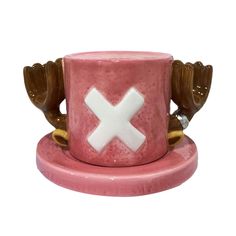 a pink cup with white x on it sitting on a saucer and two brown birds