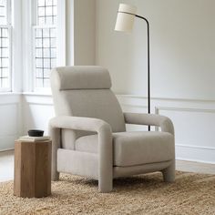 a recliner chair sitting on top of a rug next to a table with a lamp