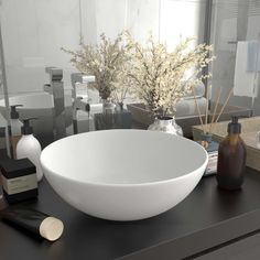 a white bowl sitting on top of a black counter next to bottles and soap dispensers