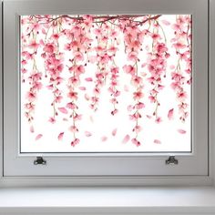 a window with pink flowers hanging from it's side, in front of a white wall