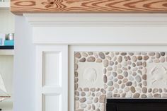 a white fireplace with rocks on it and a sailboat in the distance behind it