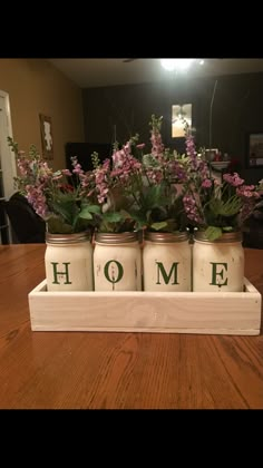 four jars with flowers in them sitting on a table