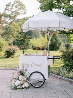 the ice cream cart is decorated with flowers and an umbrella