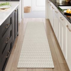 a kitchen with white cabinets and black counter tops, along with an area rug on the floor