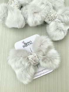 two white furry shoes with bows and glitters on the top one has a tag attached to it