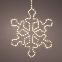 a lighted snowflake ornament hanging from a string on a gray background