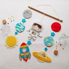 an assortment of space themed items on a white tablecloth with a wooden stick and string