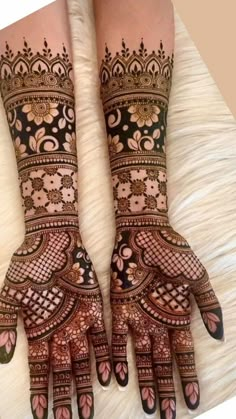 two hands that are decorated with henna designs on top of white furnishing